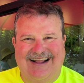 Portrait photo of man with an excellent moustache, smiling to camera.