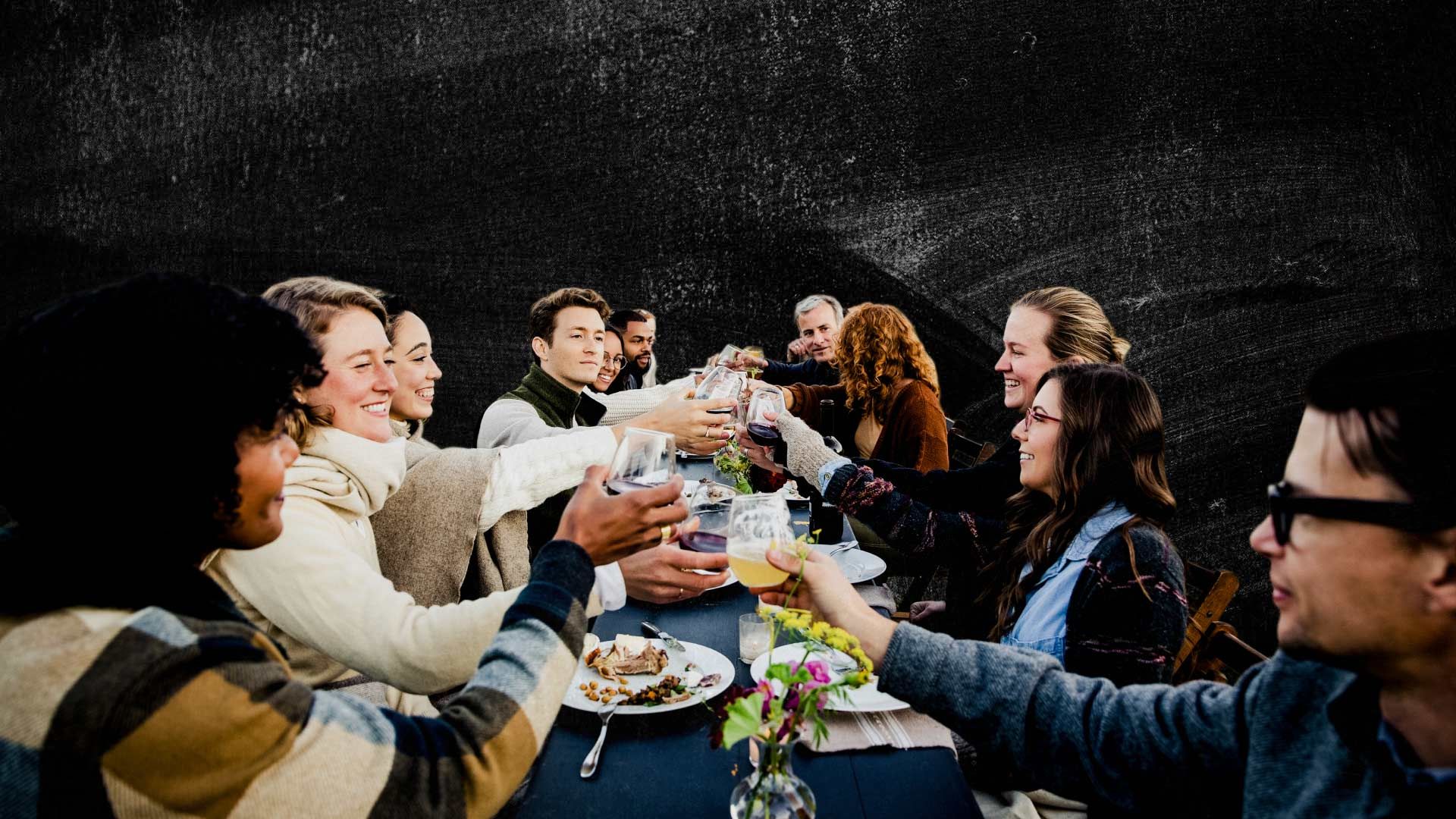 Photo of a group of people, celebrating a social gathering around a dinner table.